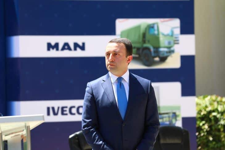 Міністр оборони Грузії на фоні плакату із автотехнікою для закупівлі